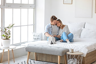Affectionate young couple relaxing on white bed in bright bedroom