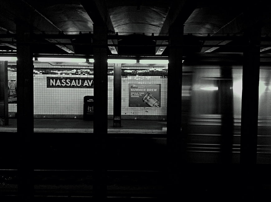 Black and white photo of Nassau Avenue subway station with moving train