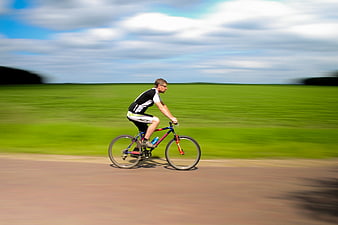 Man cycling fast on road with motion blur background