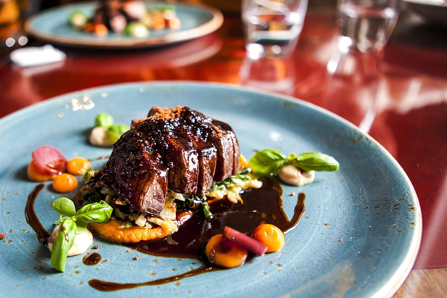 Gourmet braised meat dish with garnish on blue ceramic plate