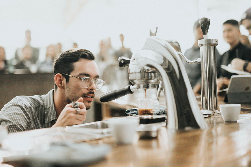 Barista making espresso in a busy coffee shop