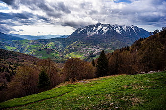 Snow-capped mountain peak overlooking green valley village
