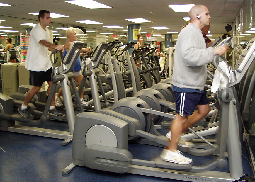People Exercising on Elliptical Machines in a Busy Gym