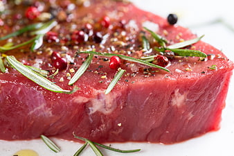 Raw marinated beef steak with rosemary and peppercorns