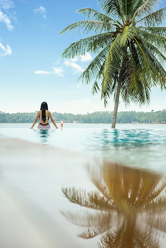 Woman in Infinity Pool with Palm Tree Reflection