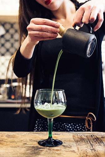 Barista pouring matcha latte into glass