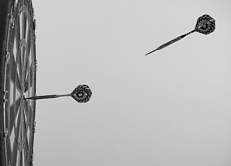 Black and white darts hitting a dartboard target