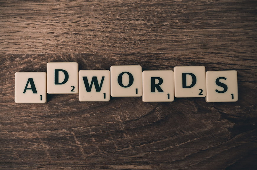 Scrabble Tiles Spelling Adwords on Wooden Background