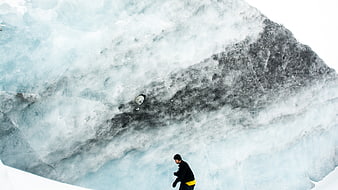 Man hiking in front of massive glacier ice wall