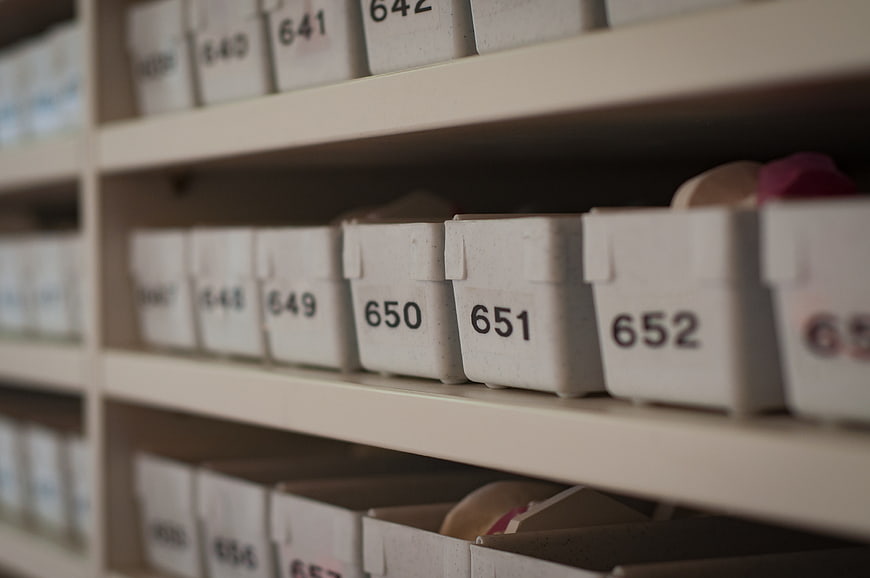 Close-up of numbered white storage bins on shelves