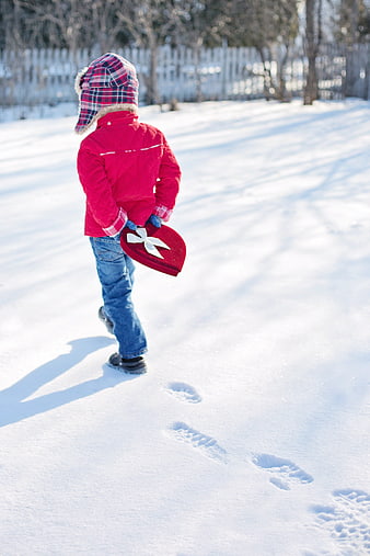 Child Walking in Snow Carrying Red Heart Gift