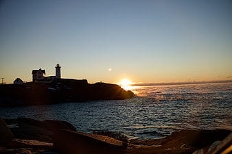 Silhouette of Lighthouse on Rocky Coast at Sunset