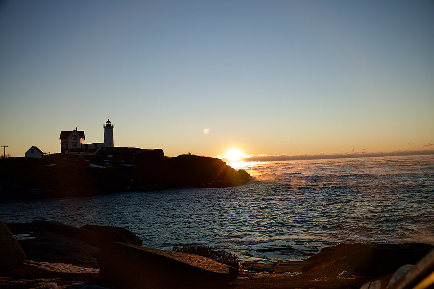 Silhouette of Lighthouse on Rocky Coast at Sunset