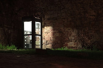 Illuminated Telephone Booth Against Stone Wall at Night