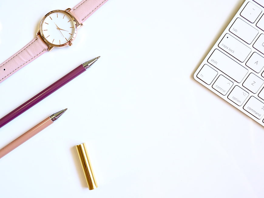 Minimalist Pink Workspace Flat Lay With Watch, Pens, and Keyboard
