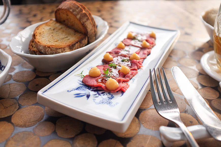 Beef carpaccio with bread on rustic wooden table