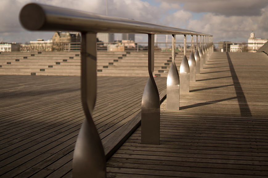 Modern metal railing on wooden deck with city skyline background