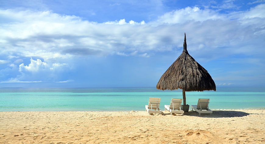 Tropical Beach with Thatched Umbrella and Lounge Chairs