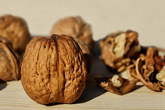 Close-up of Whole and Cracked Walnuts on Wooden Surface