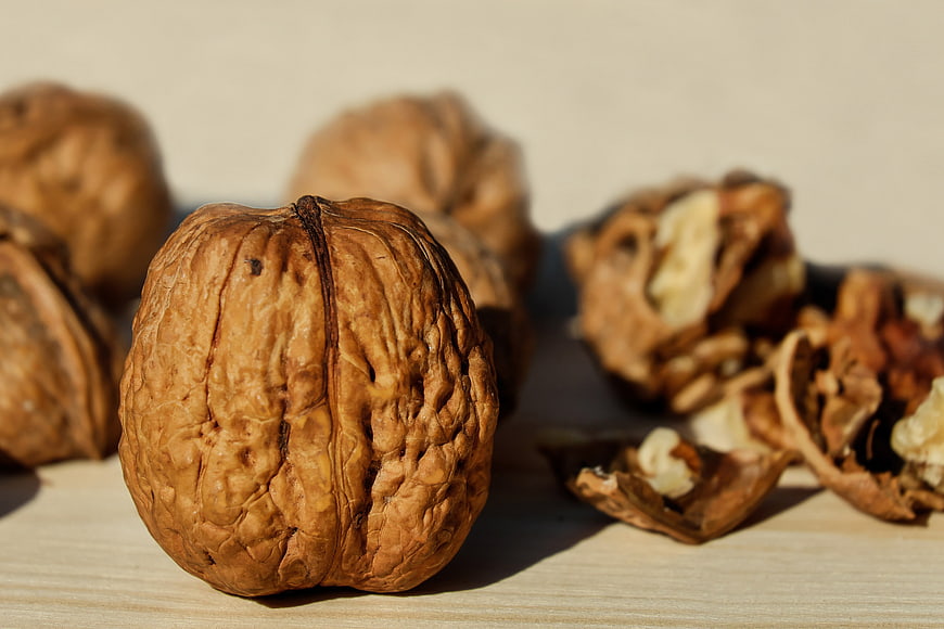 Close-up of Whole and Cracked Walnuts on Wooden Surface