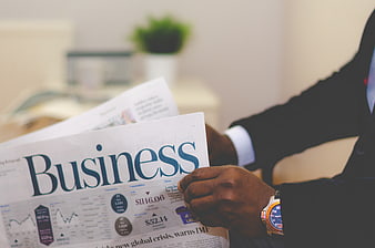 Businessman reading financial newspaper with stock market data