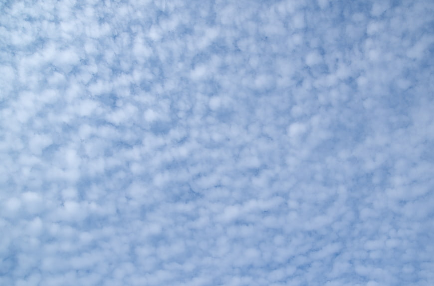 Soft blue sky with fluffy white clouds texture background