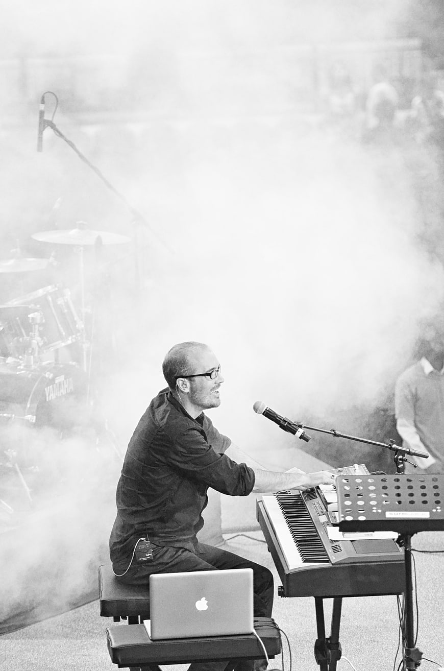 Musician playing keyboard on stage with smoke