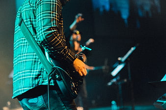 Musician playing electric guitar on stage with teal lighting