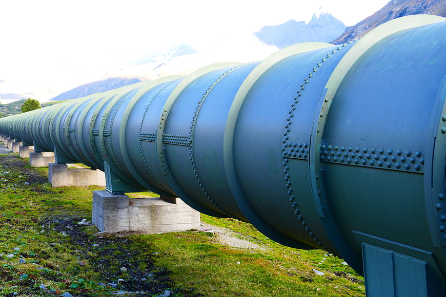Large industrial pipeline with rivets in mountain landscape