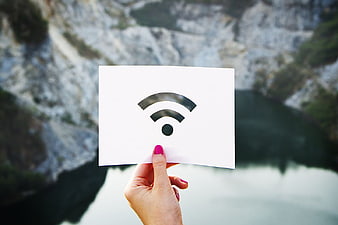 Hand holding wifi symbol card against blurred nature background