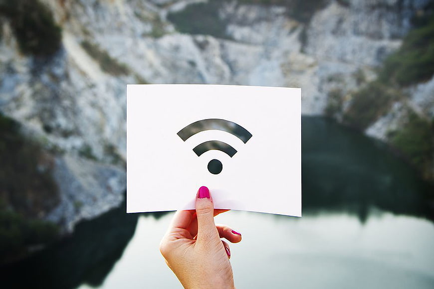 Hand holding wifi symbol card against blurred nature background