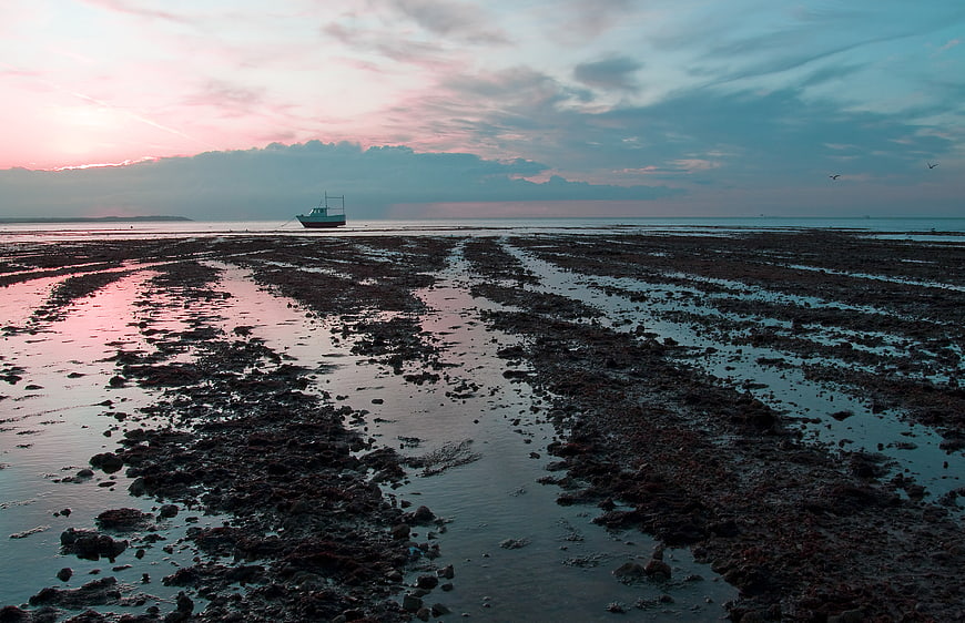 Fishing boat stranded on tidal flats at sunset