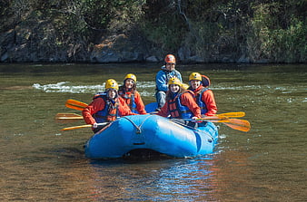 Group of people paddling a blue inflatable raft on a river