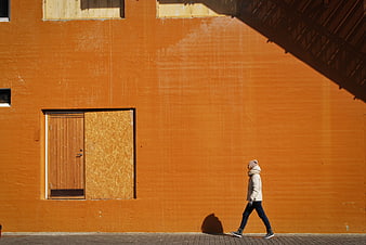 Woman Walking Past Vibrant Orange Wall