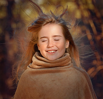 Happy Girl with Windblown Hair in Autumn Sunlight