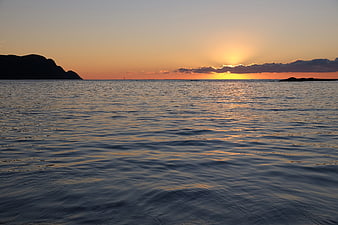 Serene Ocean Sunset with Silhouette Mountains and Golden Sky