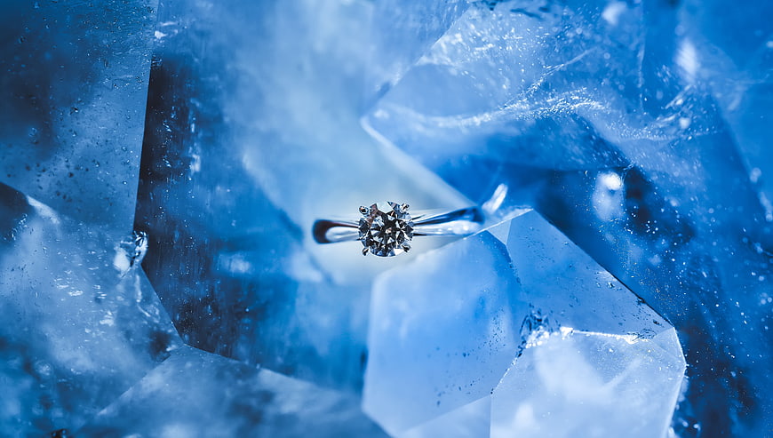 Diamond ring on blue ice crystals luxury background