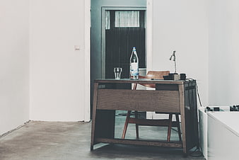 Minimalist wooden desk in modern white interior with water bottle