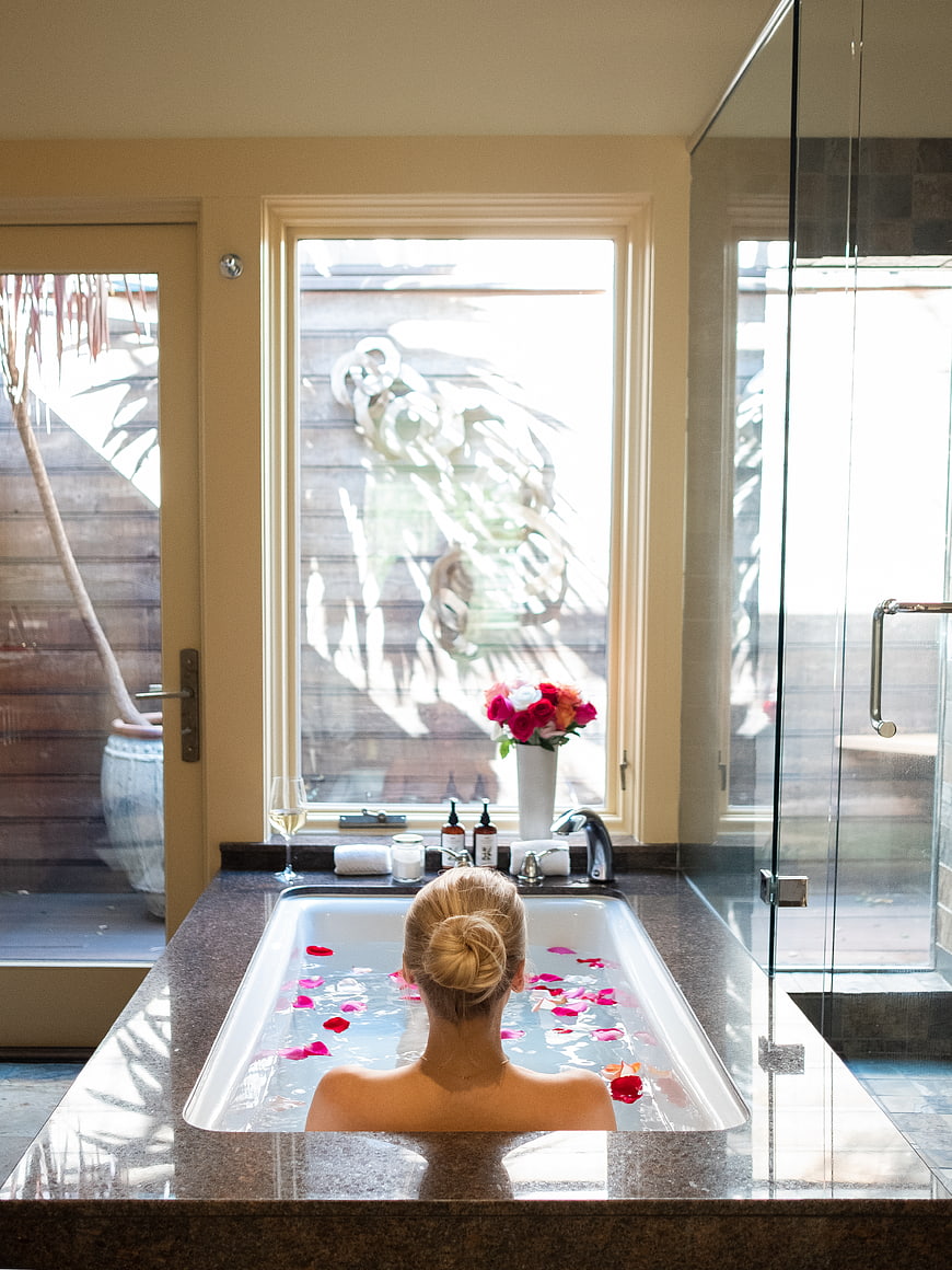 Woman relaxing in luxury bathtub with rose petals