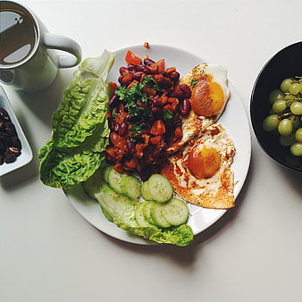 Healthy breakfast plate with fried eggs, beans, and vegetables