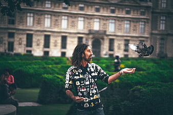 Man Feeding Flying Pigeon in Parisian Garden