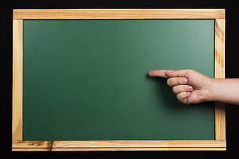 Hand pointing at blank green chalkboard with wooden frame