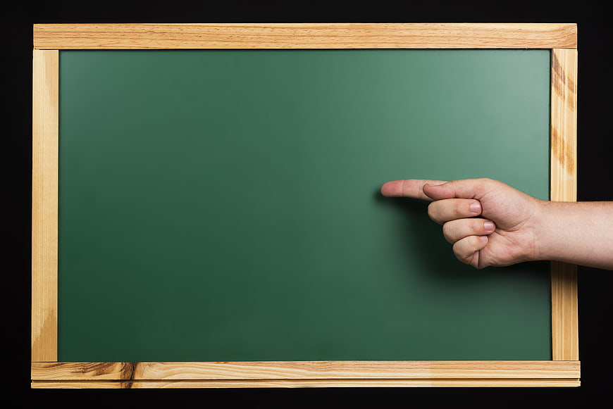 Hand pointing at blank green chalkboard with wooden frame