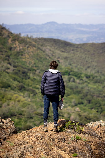 Man standing on rocky mountain peak looking at valley view