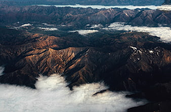 Aerial view of rugged mountain ridges above clouds