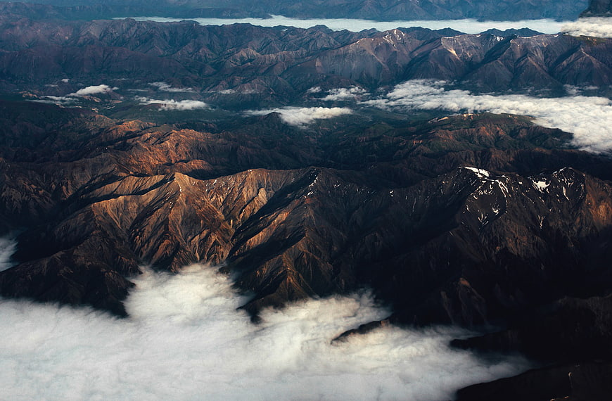 Aerial view of rugged mountain ridges above clouds
