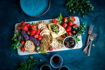 Overhead view of cheese platter with crackers and strawberries