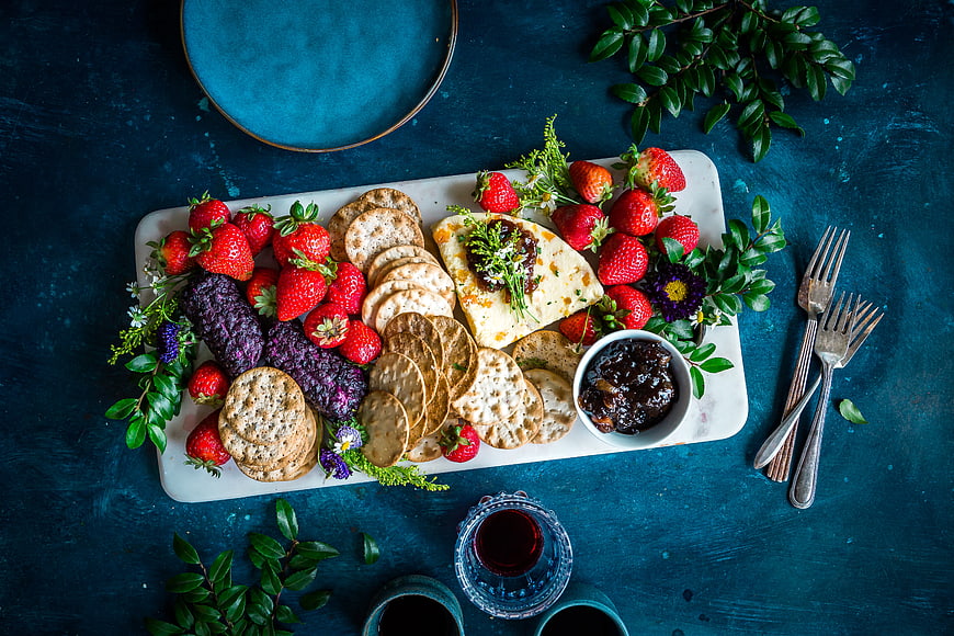Overhead view of cheese platter with crackers and strawberries