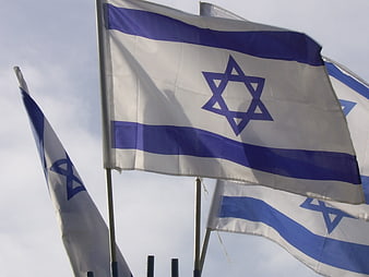 Israeli flags waving against a cloudy sky