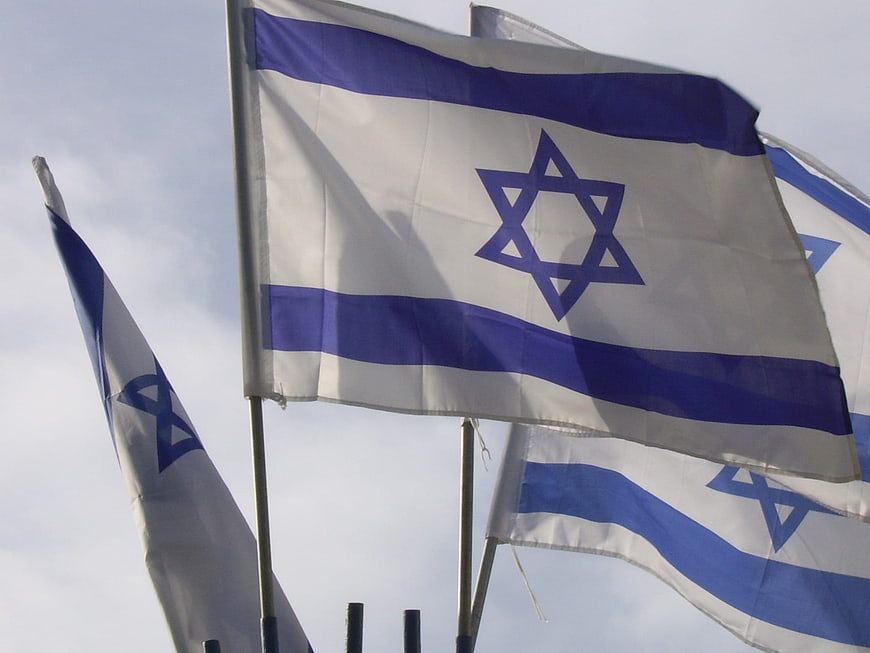 Israeli flags waving against a cloudy sky